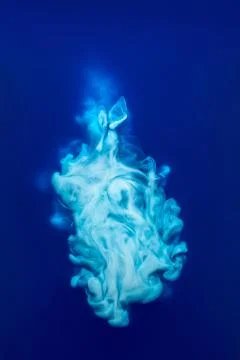 Abstract pattern falling into the water drop of blue ink - cyan ink dissolved in Stock Photos