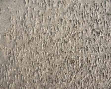 Abstract pattern made by wind in sand of sea beach Stock Photos