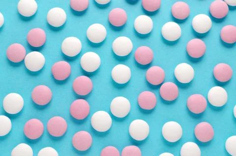 Abstract pattern of pink and white candy or pills on blue background Stock Photos