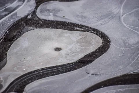 Abstract patterns of ice forming on a dark surface with water trapped under.. Foto stock