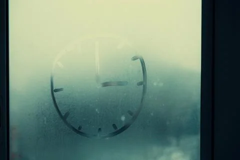An abstract picture with a clock painted on a misted window Stock Photos