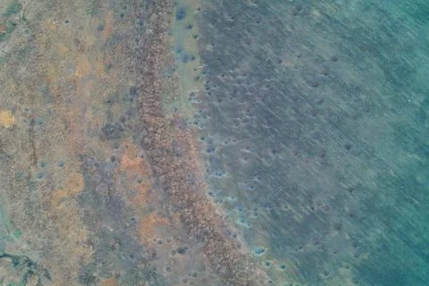 Abstract pockmarked ground texture with craters, cyan and brown wetland Stock Photos