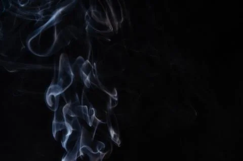 Abstract puffs of smoke on the left side of the frame on a dark background wi Stock Photos