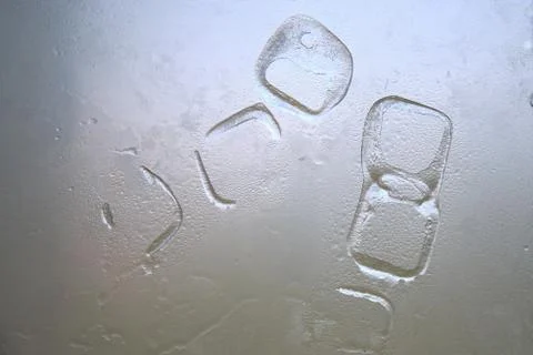 Abstract random shapes of ice cube marks on a white glass with water drops. Stock Photos
