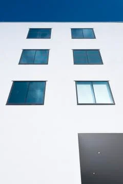Abstract rectangular forms of windows in white wall reflect blue sky and clou Stock Photos