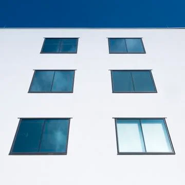 Abstract rectangular forms of windows in white wall reflect blue sky and clou 스톡 사진