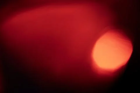 Abstract red light leak texture background against a dark backdrop. Stock Photos