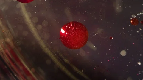 Abstract red liquid sparkling orbs floating in clear liquid bokeh background Video stock 118284356