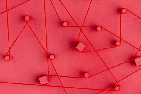 Abstract red string and wooden blocks create a complex network on a red surfa Illustrazione stock