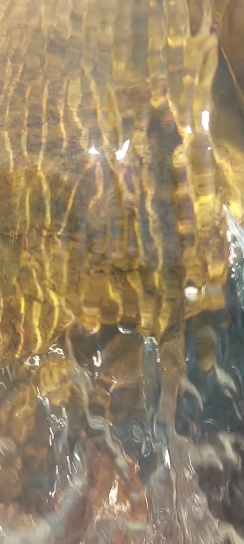 Abstract river water flowing across rocky terrain producing golden reflections Stock Footage 336763039