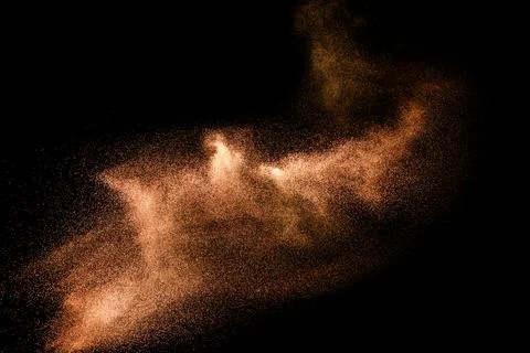 Abstract sand cloud.Brown sand splash against dark background. Brown dust e.. Stock Photos