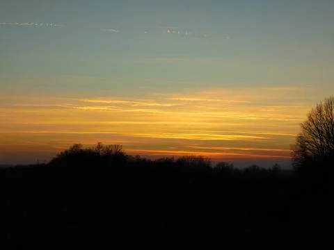 Abstract scene with shades of orange clouds during sunset above landscape. Stock Photos