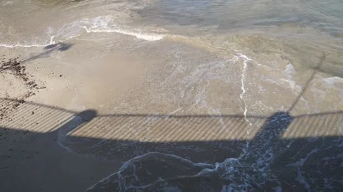 Abstract shadow of a bridge railing cast on the rippling blue water surface Stock Footage 328988936
