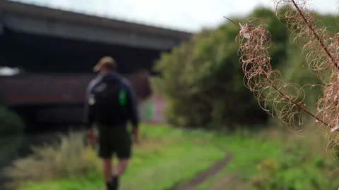 Abstract shallow focus view of a man walking along a can beside a road Vidéo 237934760