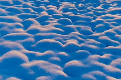 Abstract snow surface illuminated by warm sunset light, creating soft highlig Stock Photos