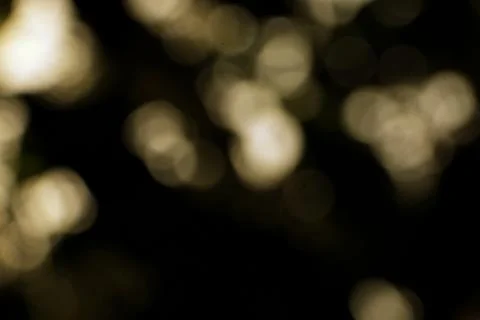 Abstract soft focus light effect with golden bokeh on black background Stock Photos