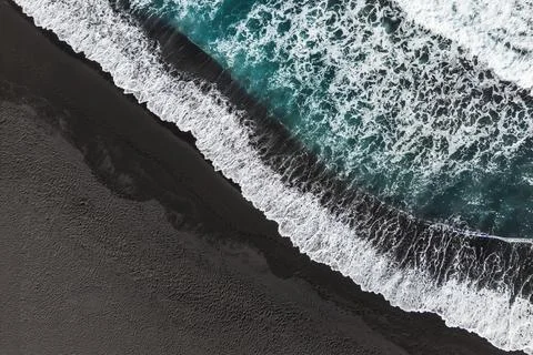 Abstract stacks of waves on black sand beach, top down view. Stock Photos
