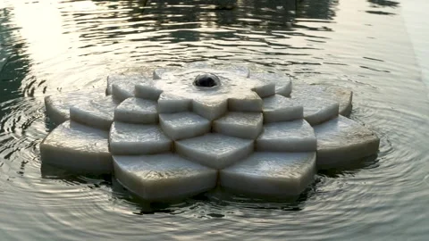 Abstract stone lotus-shaped structure in a calm water pond creating a seren.. Stock Footage 316968679