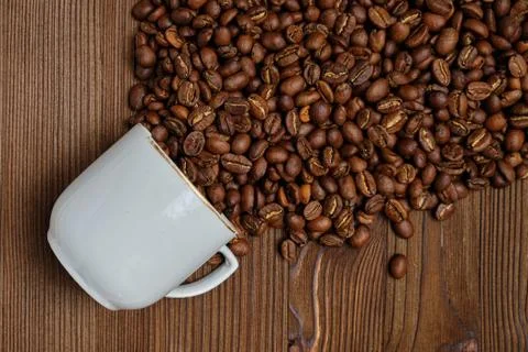An abstract stream of coffee beans made from a white cup on a wooden backgrou Stock Photos