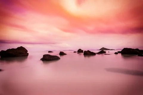 Abstract sunset scene of rock in sea with cloudscape Stock Photos