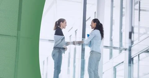 Abstract technology background against two businesswomen shaking hands at office Stockfoto's