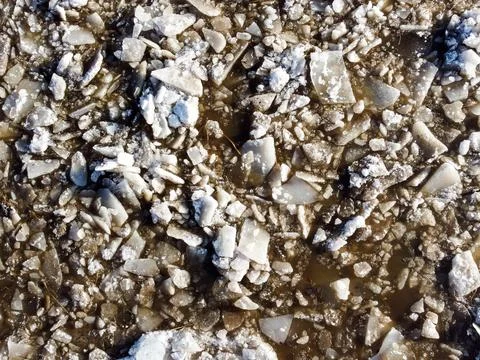 Abstract texture of broken white ice and dark water at winter. Spring is coming. Stock Photos