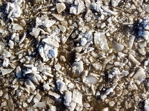 Abstract texture of broken white ice and dark water at winter. Spring is coming. Stock Photos