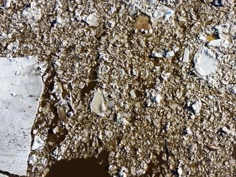 Abstract texture of broken white ice and dark water at winter. Spring is coming. Stock Photos