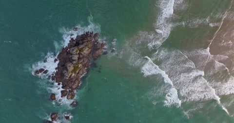 Abstract texture of ocean waves crashing together at low tide next to a rocky Stock Footage 279615610