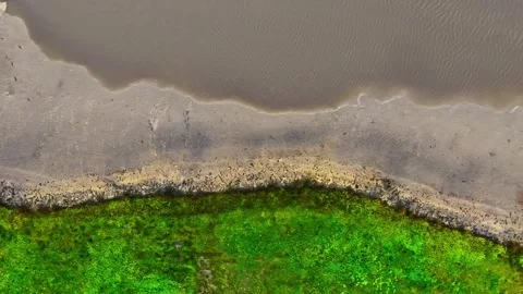 Abstract top-down view showing a river water level decreasing, unveiling muddy Stock-Footage 347707281