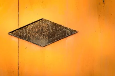 Abstract triangle with equal sides on orange colored grunge type metal Stock Photos