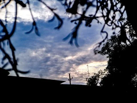 Abstract view of a cloudy sky framed by a wire mesh fence, with a cell towe.. Stock Photos