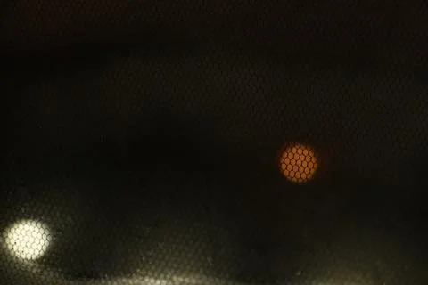 An abstract view of light filtering through a textured mesh screen at night, Foto stock