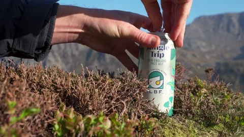 Abstract view of a person opening a can of beer outdoors in the mountains 動画素材 233301305