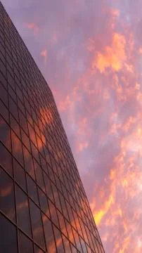 Abstract view of a skyscraper with a reflection of the evening sky and red cl Stock Photos
