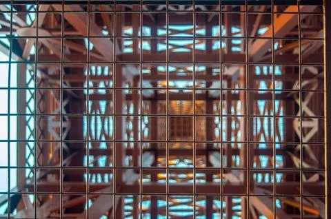 Abstract view of a tower structure through a metal grid, featuring geometri.. Stock Photos