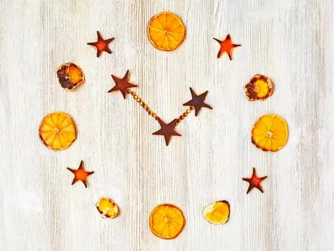 Abstract wall clock made of dried orange slices on a light wooden background. Foto stock