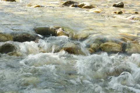 Abstract Water Background in Motion, River Stones Under Clear Flow Stock Photos