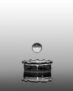Abstract water drop into container created crown, second drop about to fall Stock Photos