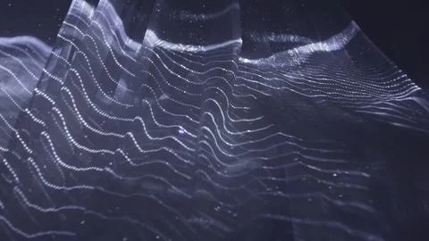 Abstract wavy surface gently moving with particles on dark background. Action Stock Photos