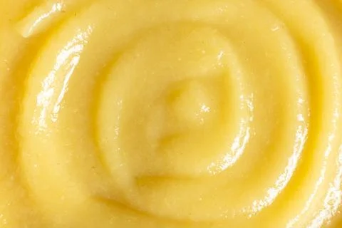 Abstract yellow fruit sauce background with swirl pattern. Stock Photos