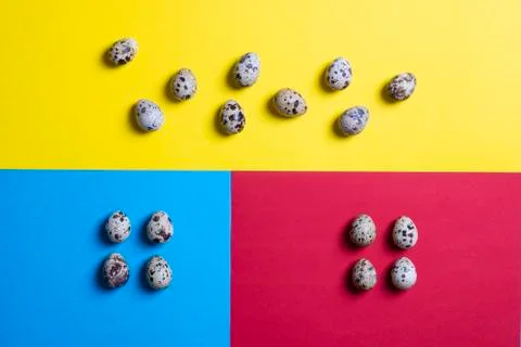 Abstraction of colorful Easter quail eggs on colorful paper. Top view with co Stock Photos