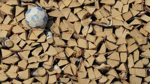Abstraction. An old soccer ball is lying on the stacked firewood. Stock-Footage 220466228