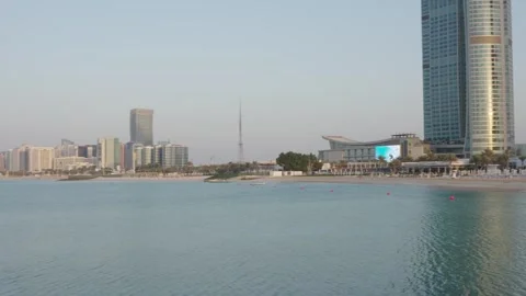 Abu Dhabi skyline with UAE flagpole on Marina Island, reflecting sunset Vidéo 331342833