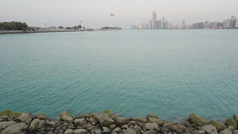 Abu Dhabi skyline with UAE flagpole on Marina Island, reflecting sunset Vidéo 331342852