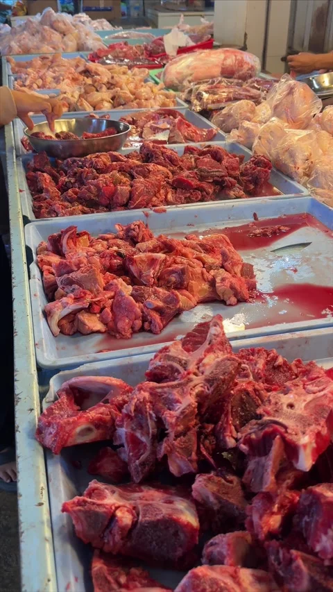 Abundant display of meticulously arranged raw meat cuts at a vibrant, bustl.. Video stock 337284582