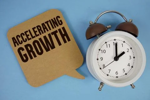 Accelerating Growth text with alarm clock on blue background Stock Photos