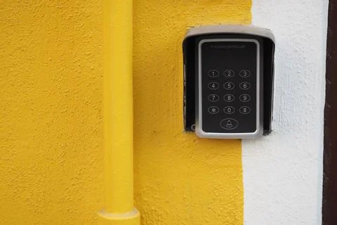Access control system mounted on a yellow wall Stock Photos