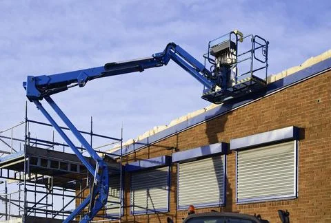 Access platform equipment powered high in sky at construction building site Stock Photos
