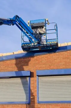 Access platform equipment powered high in sky at construction building site Stock Photos